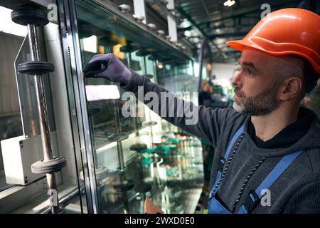 Travailleur utilise des outils spéciaux pour travailler avec le verre dans la production de fenêtres Banque D'Images