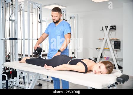 Le médecin masse les jambes d'un patient avec un masseur spécial Banque D'Images