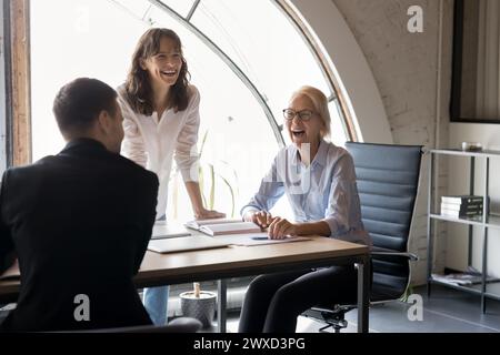 Chef aînée joyeuse et jeunes ouvriers parlant et riant Banque D'Images