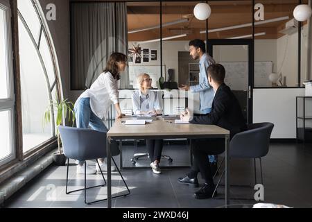 Heureux inspiré multiethnique collègues jeunes et plus âgés parlant lors de la réunion Banque D'Images