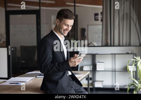 Positif jeune homme d'affaires professionnel lisant le texte sur téléphone portable Banque D'Images