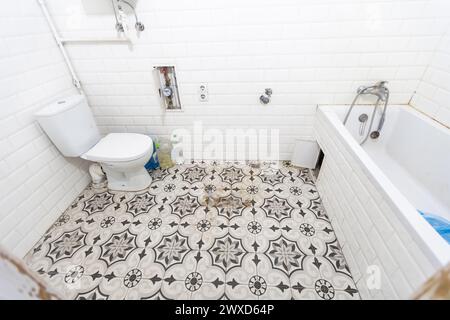 Intérieur des toilettes étroites avec toilettes murales avec murs blancs et sol en damier Banque D'Images