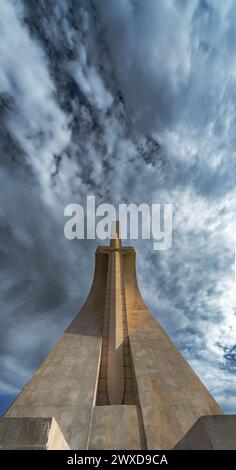 Vue de face à angle bas du Monument aux découvertes à Lisbonne avec un ciel bleu nuageux spectaculaire avec la lumière du soir illuminant la pierre swo Banque D'Images