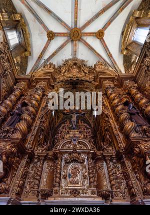 Détail d'une chapelle baroque méticuleusement sculptée dans du bois aux couleurs dorées pleines de figures religieuses avec Jésus Christ crucifié au milieu. Église Banque D'Images