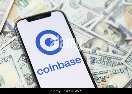 KIEV, UKRAINE - 15 MARS 2024 logo Coinbase sur l'écran d'affichage de l'iPhone avec plusieurs centaines de billets de dollars. Portail d'échange de crypto-monnaie Banque D'Images