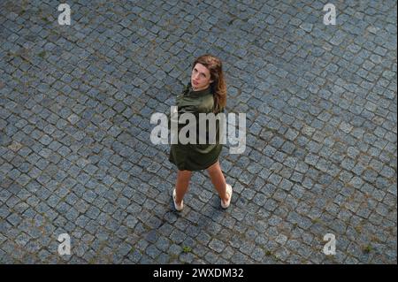La vue d'en haut de la jeune femme lève les yeux. Belle femme posant tout en se tenant debout à l'extérieur. Jeune femme heureuse profitant des vacances d'été. Vue de dessus. Banque D'Images