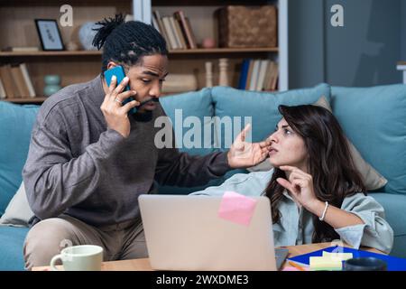 Jeunes gens d'affaires, couple, travaillant à la maison, commandant la livraison de nourriture par smartphone tout en travaillant sur un nouveau projet sur ordinateur portable. Homme affamé et Woma Banque D'Images