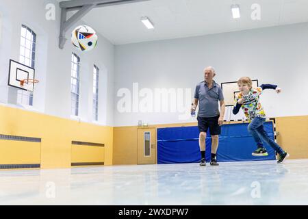 Fußball in Deutschland Göttingen, Deutschland - 26. März 2024 : Ein sieben Jahre alter Junge spielt mit seinem 82 Jahre alten Großvater Fußball mit einem offiziellen Spielball für die Euro 2024 in Deutschland mit dem Aufdruck adidas EURO24 Fußballliebe Pro. Niedersachsen Banque D'Images