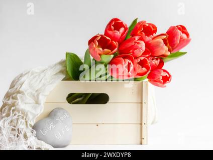 Tulipes rouges dans une boîte en bois avec un caillou qui lit Love Your Life Banque D'Images