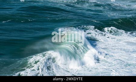 Des vagues géantes turquoises s'écrasent à la surface de l'eau formant un arc-en-ciel Banque D'Images