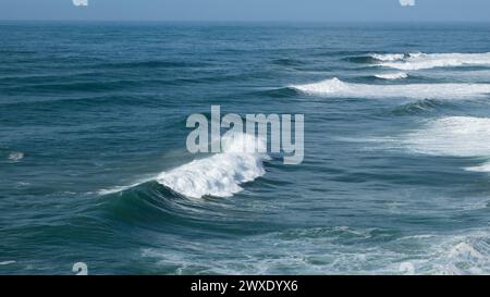 Des vagues géantes turquoises s'écrasent à la surface de l'eau formant un arc-en-ciel Banque D'Images