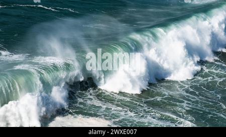 Des vagues géantes turquoises s'écrasent à la surface de l'eau formant un arc-en-ciel Banque D'Images