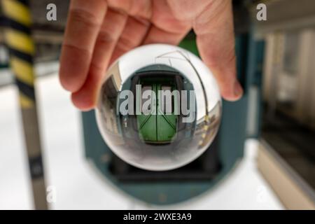 Une main tenant une boule de verre avec une porte verte au centre Banque D'Images