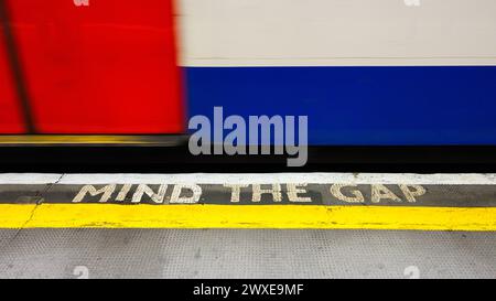 Londres, Royaume-Uni - 24 mars 2024 ; signe Mind the Gap sur le bord de la plate-forme de Londres Ungerground avec passage du train Banque D'Images