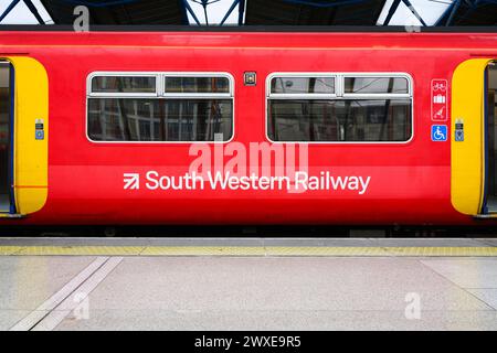 Londres, Royaume-Uni - 25 mars 2024 ; wagon de train South Western Railway avec nom et logo au quai en rouge sans personne Banque D'Images