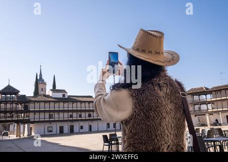 D'en bas, voyageuse anonyme d'âge moyen en gilet prenant une photo de la place historique. Sur la Plaza Mayor de Tembleque, à Tolède, dans le Don Quix Banque D'Images