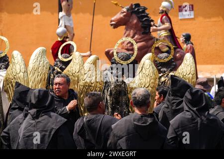 Antigua, Guatemala. 29 mars 2024. Les pénitents catholiques préparent des statues d'anges alors qu'ils s'alignent pour la procession du vendredi Saint Senor Sepultado Escuela de Cristo lors de la Semana Santa, le 29 mars 2024 à Antigua, Guatemala. Les processions opulentes sont l'une des plus grandes au monde impliquant des milliers de dévots et durant 12 heures. Crédit : Richard Ellis/Richard Ellis/Alamy Live News Banque D'Images