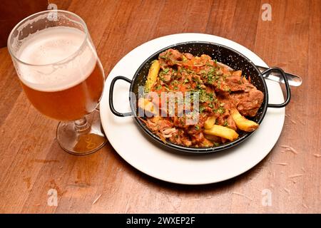 Un repas de tapas de viande mixte sur frites avec de la bière Banque D'Images