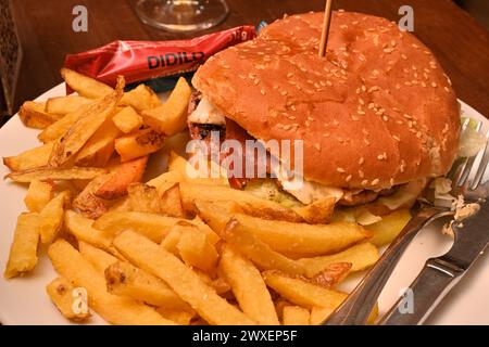 Hamburger au jambon et au fromage avec frites dans un pain aux graines de sésame Banque D'Images