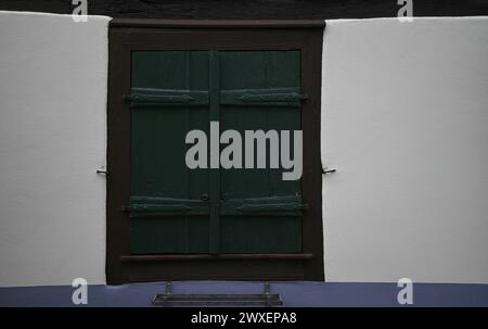 Ancienne fenêtre de maison rurale avec volets en bois vert cyprès sur un mur blanchi à la chaux dans le village pittoresque de Châtenois en Alsace, France. Banque D'Images