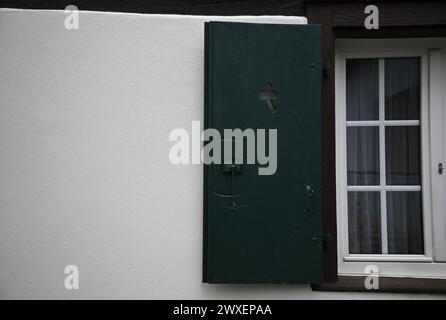 Ancienne fenêtre de maison rurale avec volets en bois vert cyprès sur un mur blanchi à la chaux dans le village pittoresque de Châtenois en Alsace, France. Banque D'Images