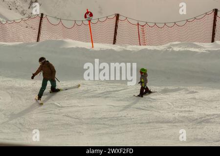 OBERSTDORF, ALLEMAGNE - 24 FÉVRIER 2024 : un homme adulte, debout sur des skis, apprend à skier un petit enfant Banque D'Images