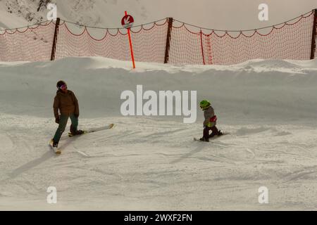 OBERSTDORF, ALLEMAGNE - 24 FÉVRIER 2024 : un homme adulte, debout sur des skis, apprend à skier un petit enfant Banque D'Images