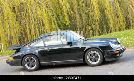 Milton Keynes, UK-Mar 30th 2024 : 1987 noir Porsche 911 Carrera coupé voiture de sport conduisant sur une route britannique Banque D'Images