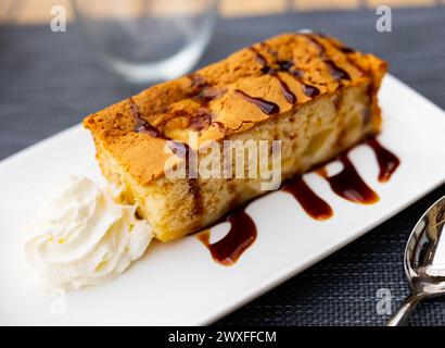 Il y a un dessert sur l'assiette - morceau rectangulaire de tarte aux pommes luxuriante avec croûte croustillante délicate et saupoudrée de sirop de cerise.Pie est complétée avec BA Banque D'Images