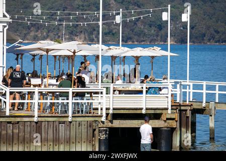 Le Joey, restaurant et café en bord de mer, les gens assis sur la terrasse en bois appréciant le déjeuner avec vue sur Pittwater, Palm Beach à Sydney, Australie, 2024 Banque D'Images