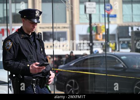 Bronx, États-Unis. 30 mars 2024. L'officier de police vérifie son téléphone sur la scène du crime. Garçon de deux ans abattu en plein jour dans le Bronx. Vers 13h44 samedi après-midi, la police est intervenue sur Fordham Road et Grand Concourse dans le Bronx, New York. La police a trouvé un garçon de deux ans souffrant d'une blessure par balle, EMS a transporté l'enfant à l'hôpital où il est inscrit dans un état stable. La police a trouvé de nombreuses douilles d'obus dans la région et recherche activement un suspect, bien que personne ne soit en détention pour le moment. Crédit : SOPA images Limited/Alamy Live News Banque D'Images