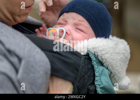 Gros plan d'un bébé qui crie et pleure et la mère essaie de calmer son enfant en plein air Banque D'Images