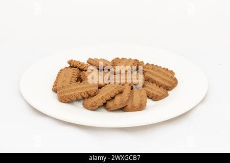 Biscuits sucrés au sucre brun foncé dans une assiette sur fond blanc isolé Banque D'Images