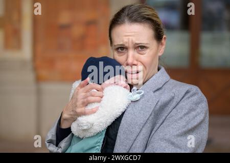 Portrait d'une mère de fin de terme extrêmement épuisée et stressée dans ses 40 ans tenant son nouveau-né et pleurant devant la caméra à l'extérieur Banque D'Images