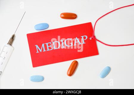 Concept médical. MEDIGAP sur un carton rouge avec une corde sur fond blanc Banque D'Images