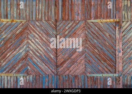 texture de porte de vieilles planches en bois avec des couches de peinture marron et bleue pelées sous une couche de peinture bleue blanchie par le soleil Banque D'Images