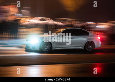 SYMBOLE - 29 mars 2024, Rhénanie-Palatinat, Nürburg : une voiture roule sur une route dans le noir sur ce que l'on appelle le «vendredi de la voiture» au Nürburgring. Car Friday' est l'ouverture de la saison pour les fans de voitures. Photo : Silas Stein/dpa Banque D'Images