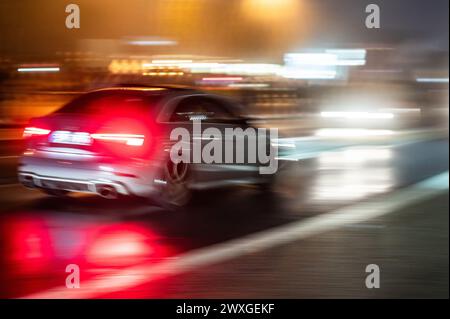 SYMBOLE - 29 mars 2024, Rhénanie-Palatinat, Nürburg : une voiture roule sur une route dans le noir sur ce que l'on appelle le «vendredi de la voiture» au Nürburgring. Car Friday' est l'ouverture de la saison pour les fans de voitures. Photo : Silas Stein/dpa Banque D'Images