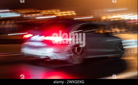 SYMBOLE - 29 mars 2024, Rhénanie-Palatinat, Nürburg : une voiture roule sur une route dans le noir sur ce que l'on appelle le «vendredi de la voiture» au Nürburgring. Car Friday' est l'ouverture de la saison pour les fans de voitures. Photo : Silas Stein/dpa Banque D'Images
