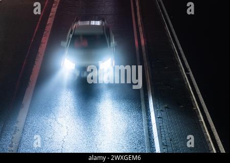 SYMBOLE - 29 mars 2024, Rhénanie-Palatinat, Nürburg : une voiture roule sur une route dans le noir sur ce que l'on appelle le «vendredi de la voiture» au Nürburgring. Car Friday' est l'ouverture de la saison pour les fans de voitures. Photo : Silas Stein/dpa Banque D'Images