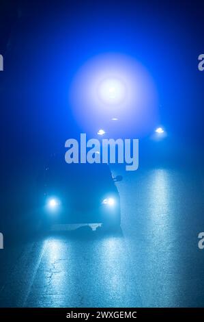 SYMBOLE - 29 mars 2024, Rhénanie-Palatinat, Nürburg : une voiture de police roule derrière un véhicule sur une route dans l'obscurité avec des feux bleus clignotants sur le "vendredi voiture" au Nürburgring. Car Friday' est l'ouverture de la saison pour les fans de voitures. Photo : Silas Stein/dpa Banque D'Images