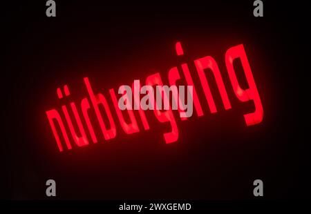 SYMBOLE - 29 mars 2024, Rhénanie-Palatinat, Nürburg : le lettrage Nürburgring est illuminé sur une façade dans l'obscurité sur ce que l'on appelle le "vendredi de la voiture" au Nürburgring. Photo : Silas Stein/dpa Banque D'Images