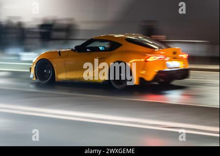 SYMBOLE - 29 mars 2024, Rhénanie-Palatinat, Nürburg : une voiture roule sur une route dans le noir sur ce que l'on appelle le «vendredi de la voiture» au Nürburgring. Car Friday' est l'ouverture de la saison pour les fans de voitures. Photo : Silas Stein/dpa Banque D'Images