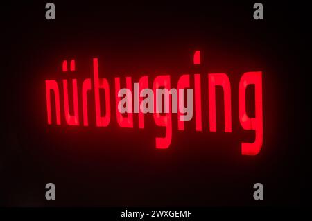SYMBOLE - 29 mars 2024, Rhénanie-Palatinat, Nürburg : le lettrage Nürburgring est illuminé sur une façade dans l'obscurité sur ce que l'on appelle le "vendredi de la voiture" au Nürburgring. Photo : Silas Stein/dpa Banque D'Images