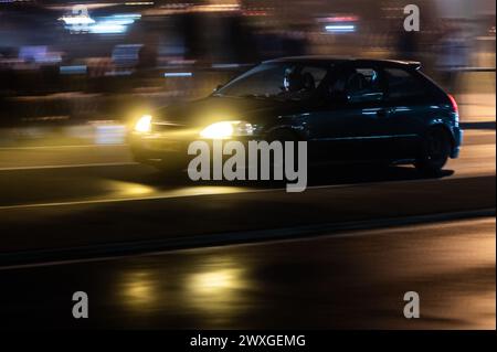 SYMBOLE - 29 mars 2024, Rhénanie-Palatinat, Nürburg : une voiture roule sur une route dans le noir sur ce que l'on appelle le «vendredi de la voiture» au Nürburgring. Car Friday' est l'ouverture de la saison pour les fans de voitures. Photo : Silas Stein/dpa Banque D'Images