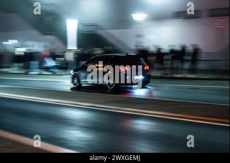 SYMBOLE - 29 mars 2024, Rhénanie-Palatinat, Nürburg : une voiture roule sur une route dans le noir sur ce que l'on appelle le «vendredi de la voiture» au Nürburgring. Car Friday' est l'ouverture de la saison pour les fans de voitures. Photo : Silas Stein/dpa Banque D'Images