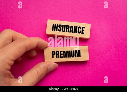 Mots de prime d'assurance écrits sur des blocs de bois avec fond rose. Symbole conceptuel. Copier l'espace. Banque D'Images