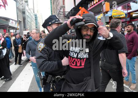 Des membres du département de police de la ville de New York tiennent un manifestant pro-israélien lors d'un rassemblement à Times Square dans le but de prévenir les affrontements entre manifestants pro-palestiniens et pro-israéliens. Des manifestants pro-palestiniens se sont rassemblés à Manhattan, New York City, condamnant les opérations militaires des Forces de défense israéliennes à Gaza. Le rassemblement a eu lieu le jour de la Terre pour commémorer une manifestation de 1976 contre les plans du gouvernement israélien de contrôler des terres appartenant à des Arabes dans la région nord de la Galilée. La police israélienne a abattu six Palestiniens lors de la manifestation de 1976. Chaque année, la Journée de la Terre symbolise la résistance palestinienne Banque D'Images