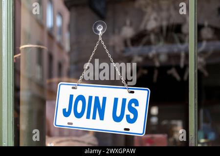 Gros plan sur un panneau bleu dans une fenêtre avec écrit dedans 'Rejoignez-nous'. Banque D'Images