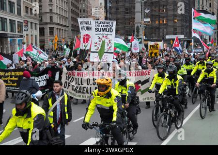 Des manifestants pro-palestiniens défilent en portant des pancartes et des banderoles exprimant leurs opinions tandis que des membres du département de police de New York font du vélo et suivent la marche. Des manifestants pro-palestiniens se sont rassemblés à Manhattan, New York City, condamnant les opérations militaires des Forces de défense israéliennes à Gaza. Le rassemblement a eu lieu le jour de la Terre pour commémorer une manifestation de 1976 contre les plans du gouvernement israélien de contrôler des terres appartenant à des Arabes dans la région nord de la Galilée. La police israélienne a abattu six Palestiniens lors de la manifestation de 1976. Chaque année, la Journée de la Terre symbolise la résistance palestinienne à Israël. Si Banque D'Images